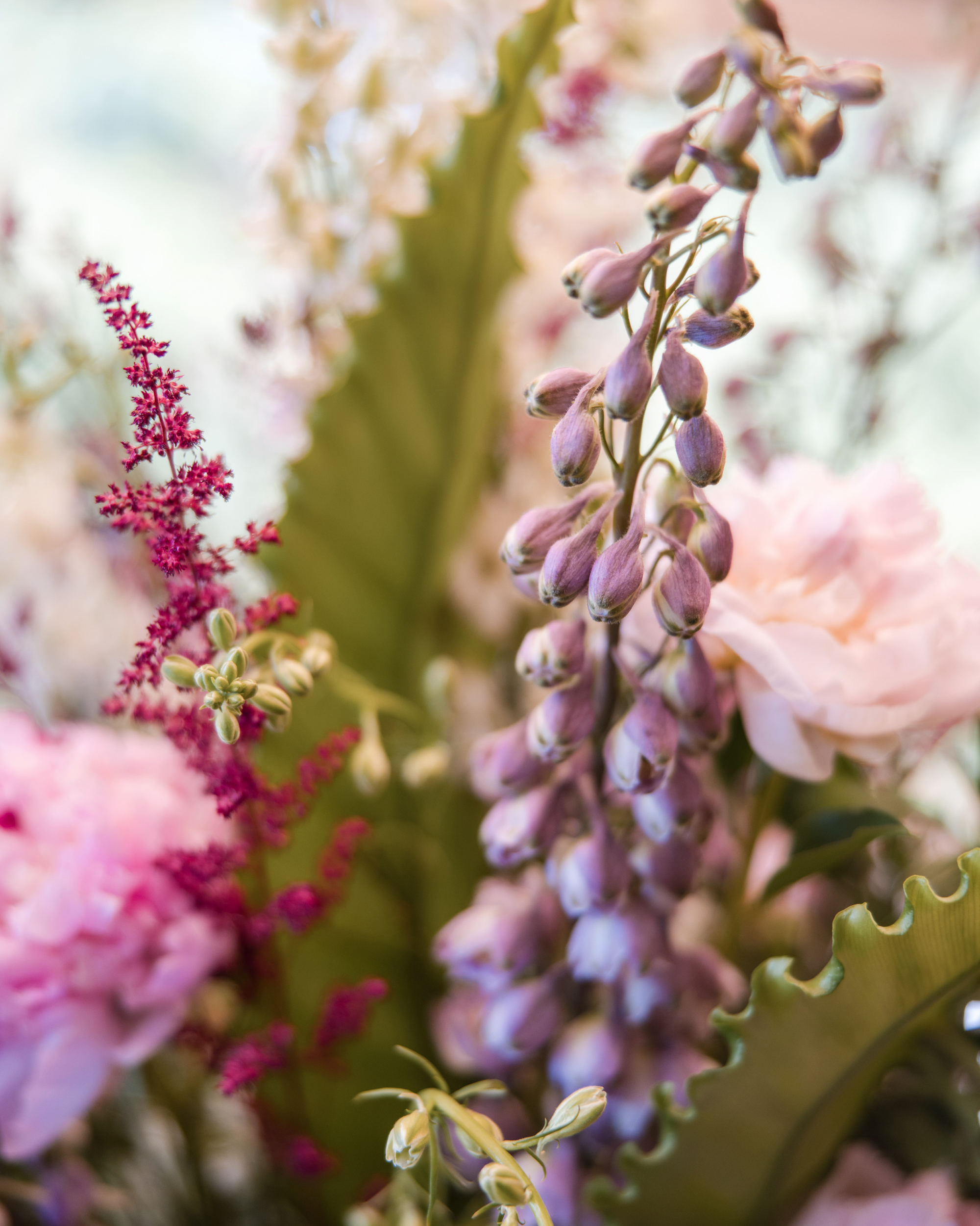 Close-up of a floral arrangement featuring pink peonies, purple delphiniums, and assorted greenery—perfect for a Longwood Gardens welcome party.