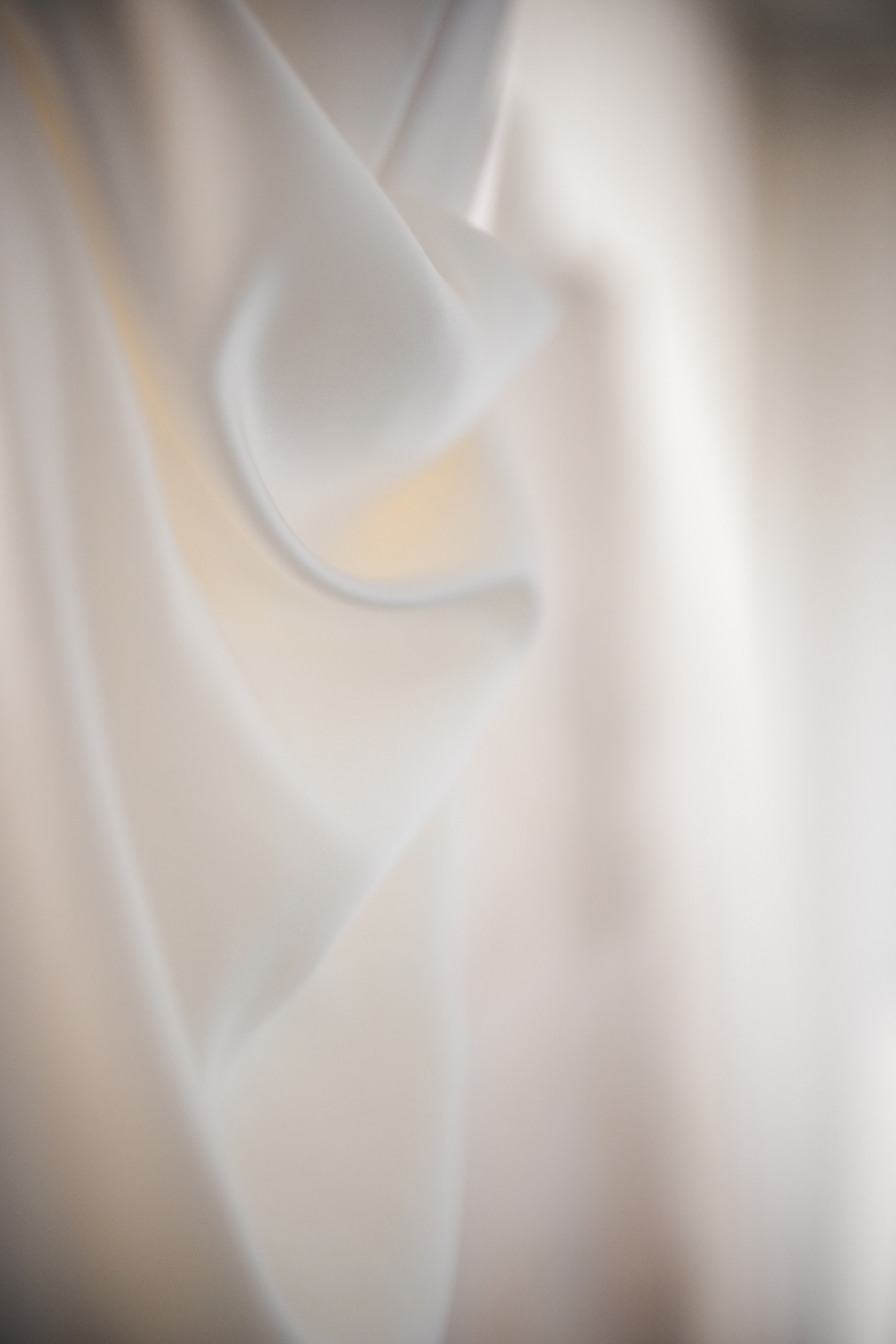 Close-up of soft, white fabric with gentle folds, reminiscent of a Lotte New York Palace wedding, set against a blurred background.