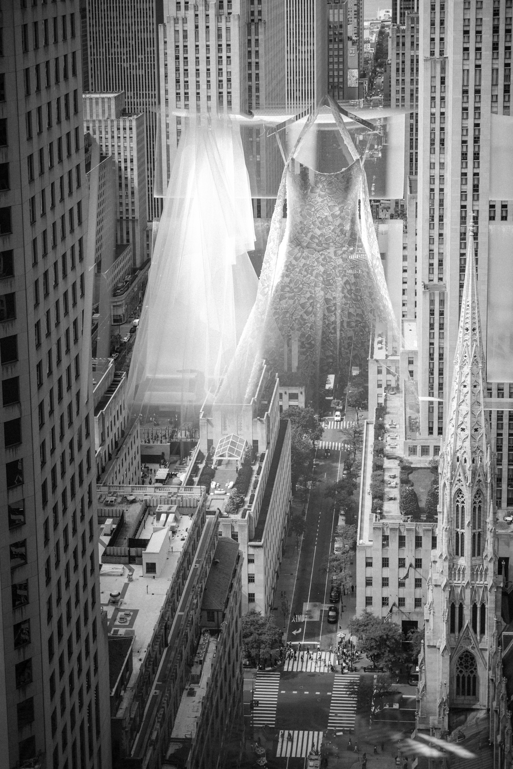 A cityscape with tall buildings is overlaid by the reflection of two wedding dresses, including a veil, seen in a window—evoking the elegance of a Guastavino’s wedding.
