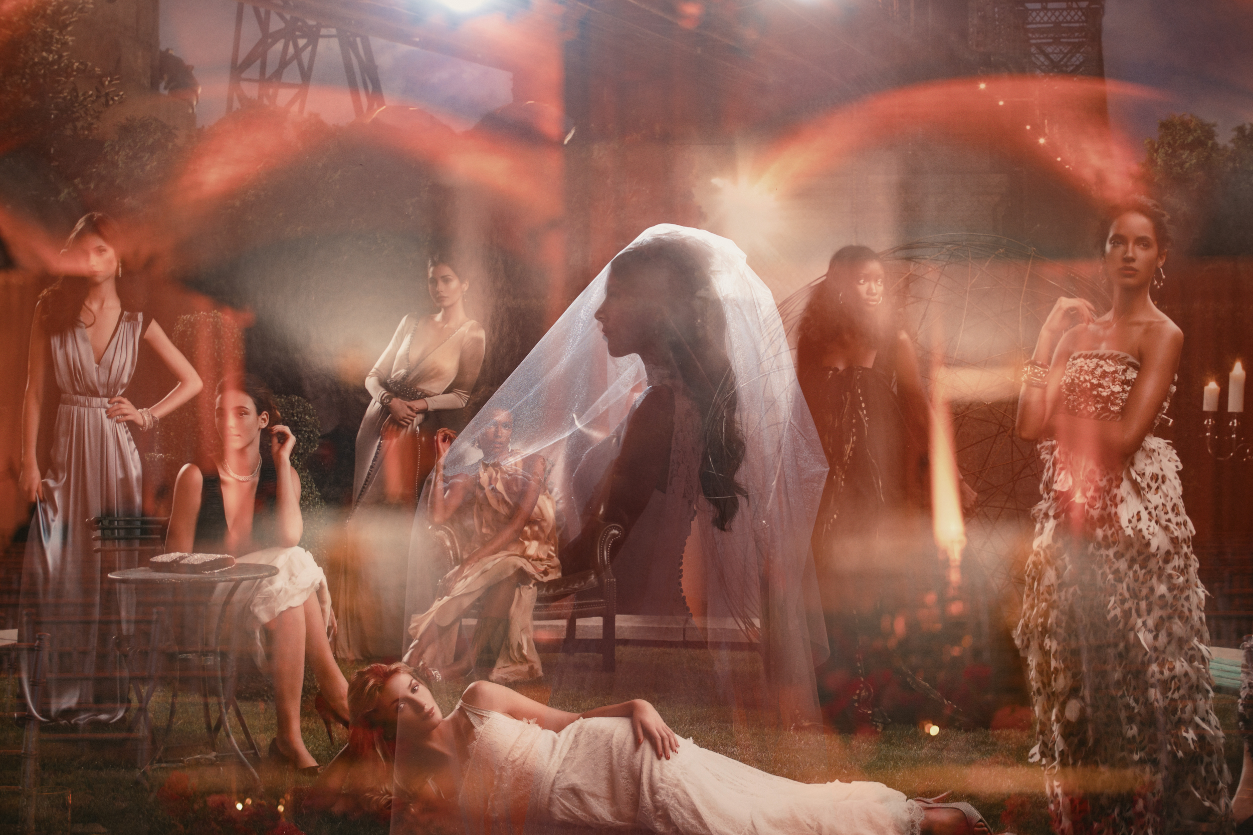 A group of women in formal dresses pose in a dramatic, artfully lit scene with layered, blurred light effects and one woman in a bridal veil, capturing the enchanting atmosphere of a Guastavino’s wedding.